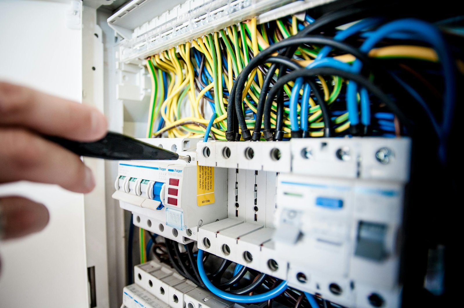 Electrician wiring fuse box wearing safety gear